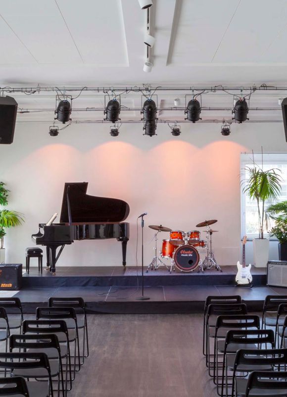 Auditorium della Scuola di Musica Cluster con pianoforte, batteria e sedie allestite per l’Open Day